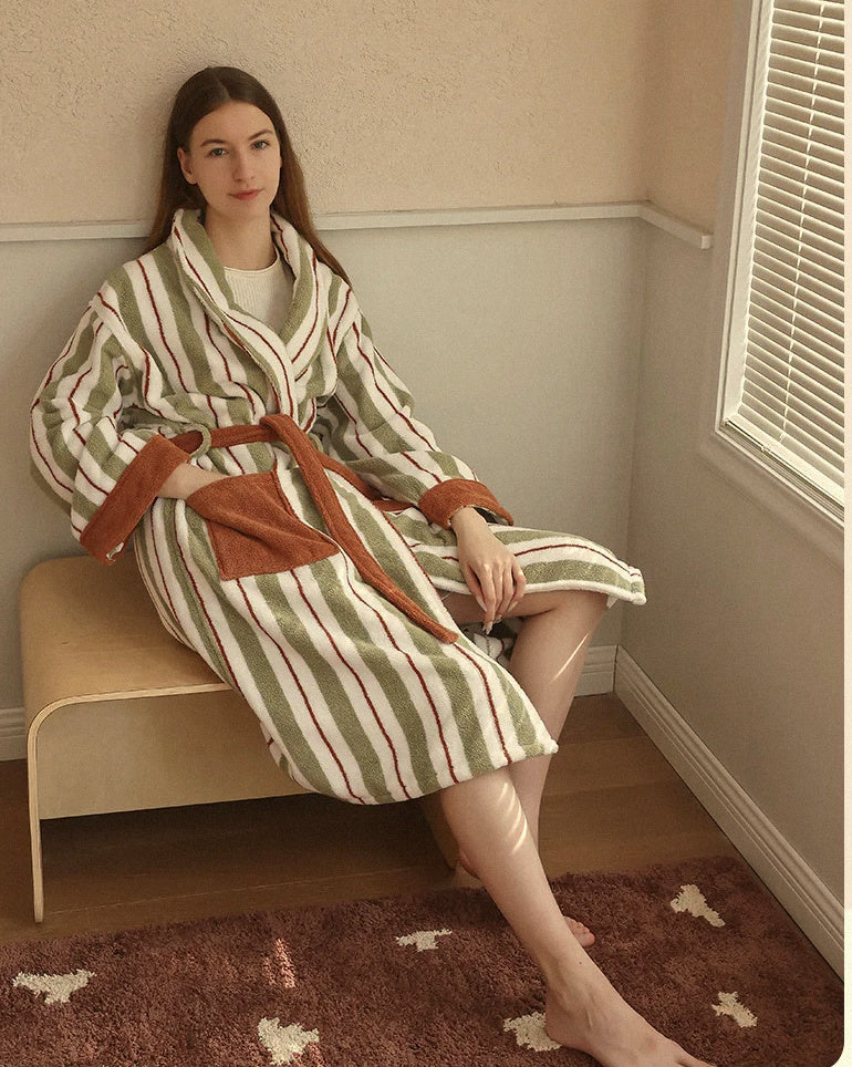 Femme assise en peignoir long éponge de coton rayé vert sauge et terracotta, Heure Sauvage, lumière naturelle