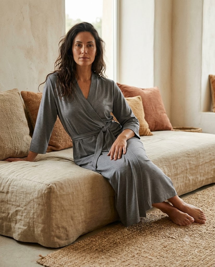 Femme assise en peignoir long en maille jersey gris cendre, col croisé et ceinture nouée, peignoir femme Heure Sauvage
