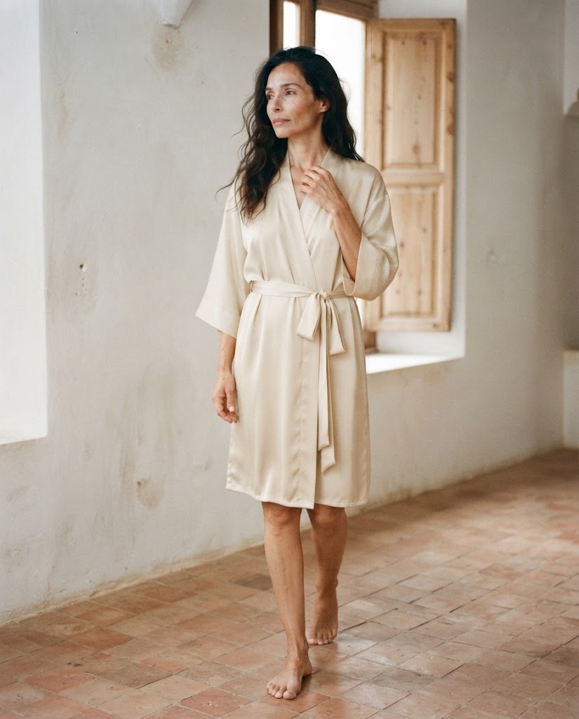 Femme en peignoir court en satin écru, col croisé et ceinture nouée