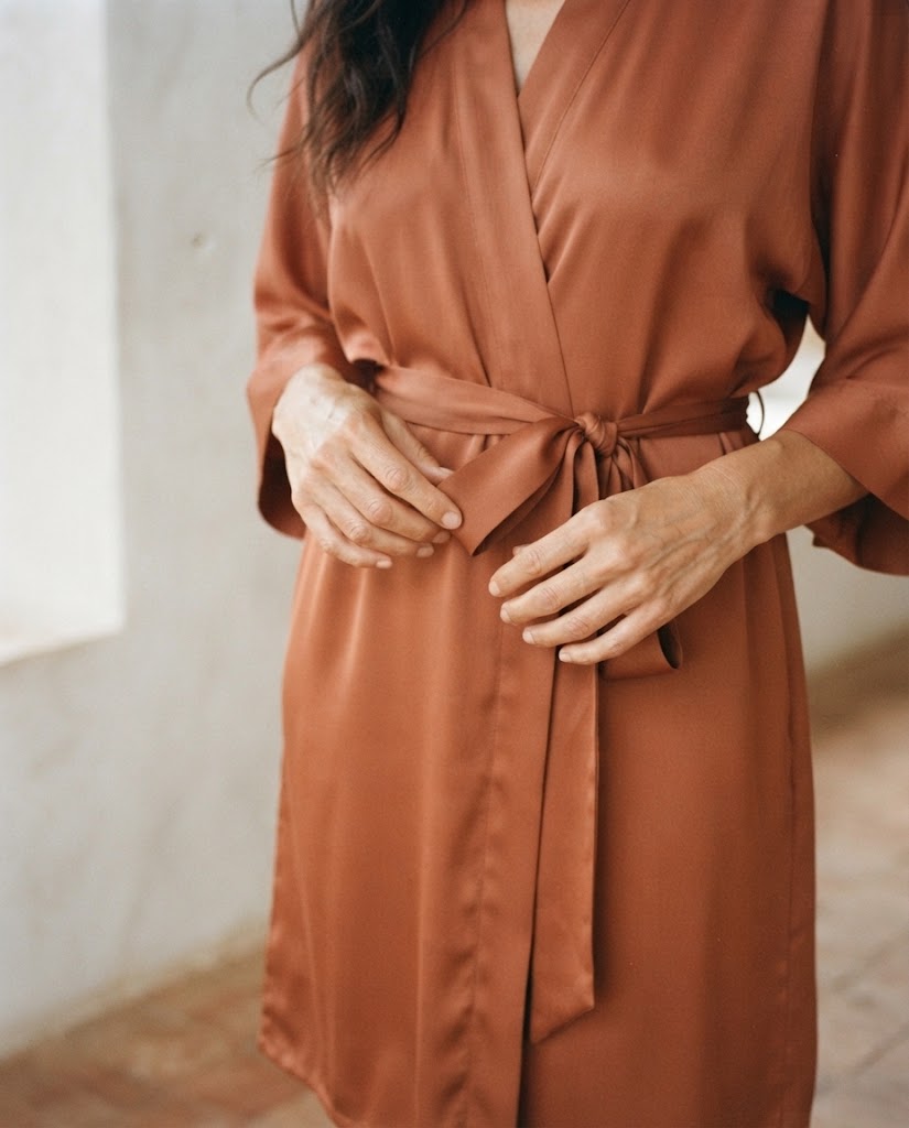 Gros plan sur la ceinture nouée d'un peignoir femme en satin terracotta