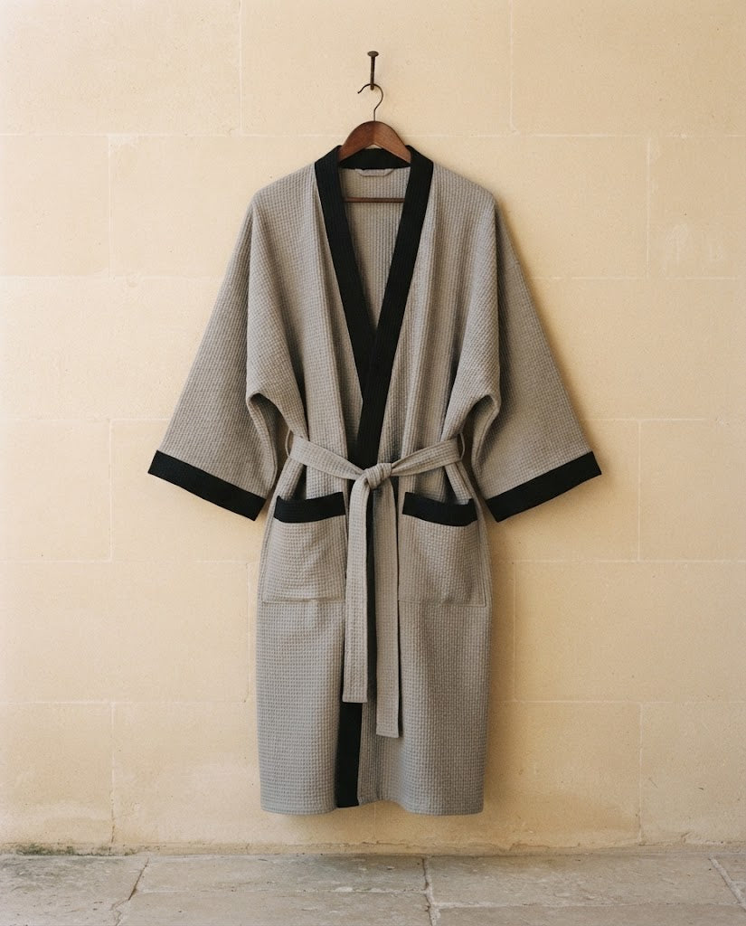 Peignoir homme maille gaufrée gris à parement noir sur cintre, grande taille, mur en pierre claire, Heure Sauvage