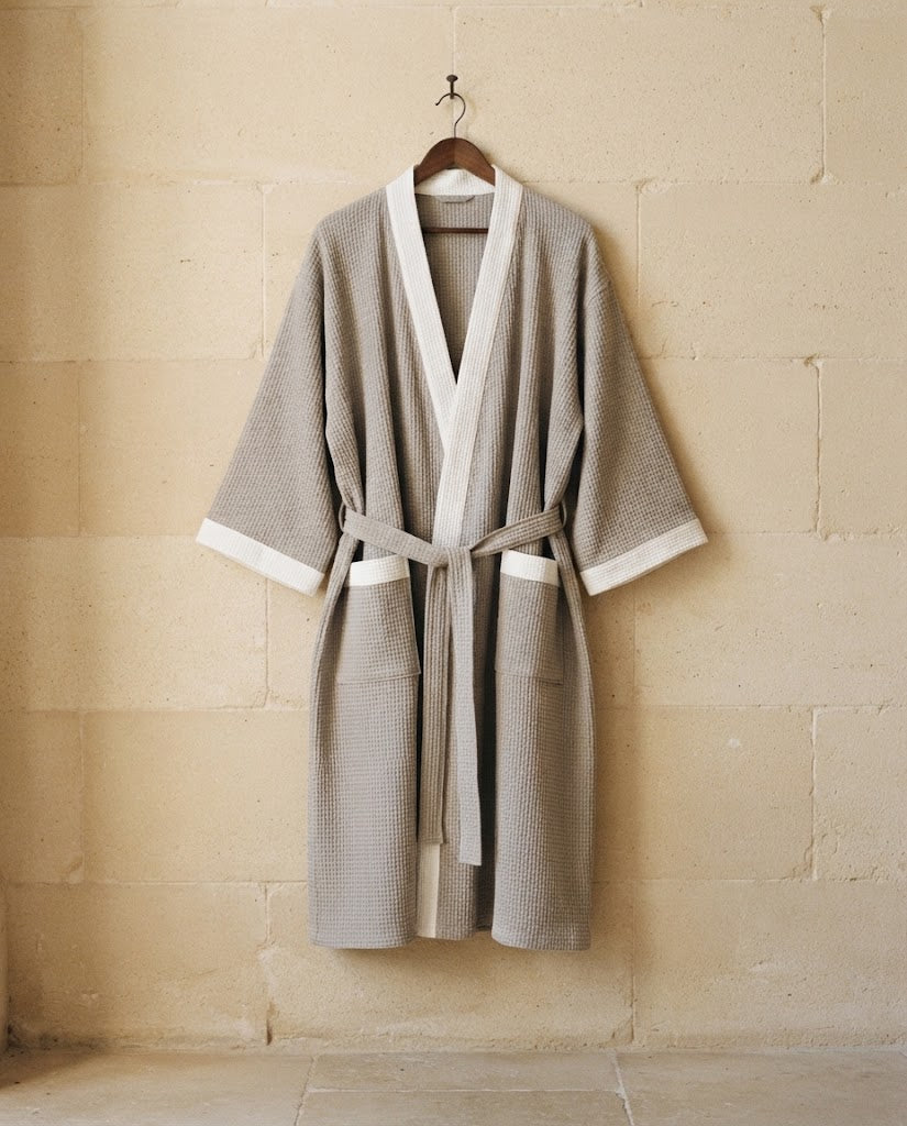Peignoir homme maille gaufrée gris à parement blanc sur cintre, grande taille, mur en pierre claire, Heure Sauvage