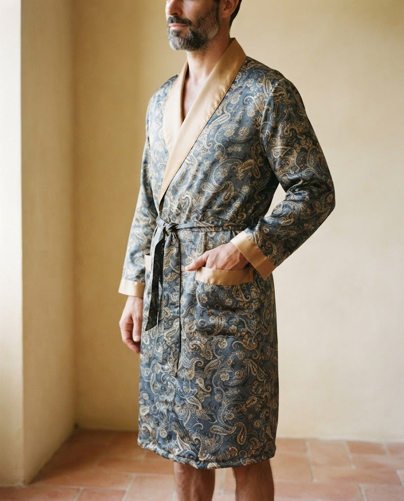 Détail d'une robe de chambre homme en satin paisley, col châle et poches bordés de satin doré, main dans la poche