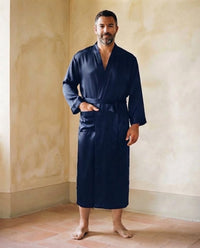 Homme en robe de chambre légère en satin bleu marine à col kimono, debout pieds nus sur des tomettes